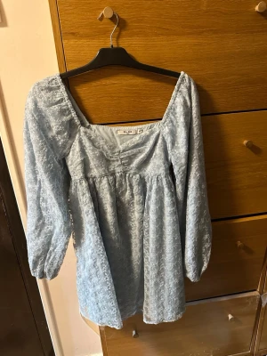 NA-KD blå klänning - Säljer denna superfina blåa långärmade klänningen från NA-KD! Endast blivit använd en gång på en konsert för något år sedan! Storlek 34, hör av er om ni har några funderingar!🤍