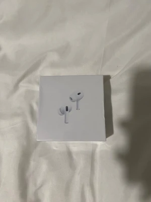 Apple AirPods Pro 2 USB-C - Säljer ett par Apple AirPods Pro 2nd generation med magnetiskt laddningsetui och USB-C. De är vita och har en stilren, kompakt design som är perfekt för trådlös musik och samtal. Materialet är plast och de är riktigt smidiga att ta med sig överallt.