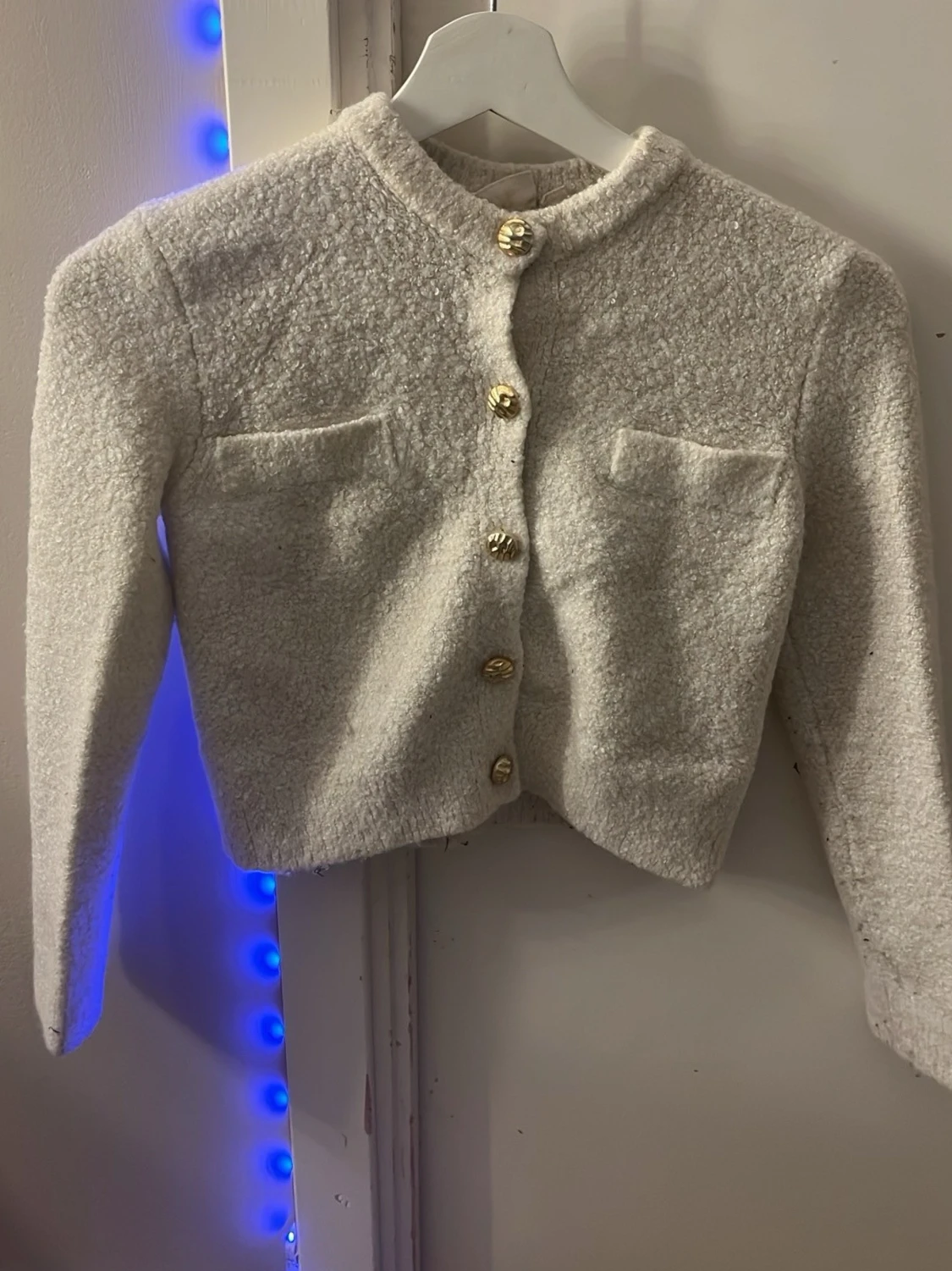 Vit bouclékofta med guldknappar