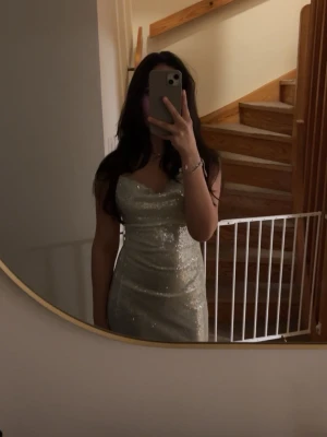 Ljus grön långklänning - Säljer en ljus grön balklänning med smala axelband och figurnära passform. Man kan ändra passformen med banden där bak. Den är ifrån Design By Si och är i storlek XS/S.                Perfekt som balklänning💕