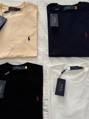 Polo Ralph Lauren t-shirt i flera färger - Klassiska t-shirts från Polo Ralph Lauren i beige, marinblå, svart och vit. Alla har rund hals, korta ärmar och den ikoniska broderade loggan på bröstet. Perfekt basplagg med stilren design och mjuk bomullskvalitet.