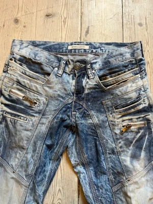 Washed Jeans från Dsquared2 - W29 L34. Säljer ett par blå washed jeans från Dsquared2 med flera dragkedjor och detaljerade sömmar. Jeansen har en unik tvättad look, raka ben och coola fickor med dragkedjor framtill. Perfekta för dig som gillar streetwear och statement-plagg.