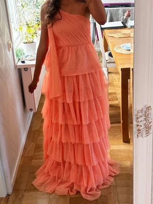 Korallrosa balklänning  - Jättefin balklänning jag använt en gång! Den är off shoulder på ena armen med snören man kan låta hänga eller knyta! 🤍