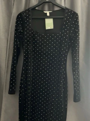 Svart sammetsklänning med pärlor H&M - Supersnygg svart sammetsklänning från H&M med långa ärmar och fyrkantig ringning. Klänningen är täckt av små pärlor som ger ett glittrigt intryck. Perfekt för dig som vill sticka ut! Materialet är mjukt sammet och modellen är kroppsnära.