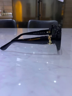 Svarta runda solglasögon från YSL - Snygga svarta solglasögon från Yves Saint Laurent med oval form och mörka glas. Köptes för ca 4000 kr.