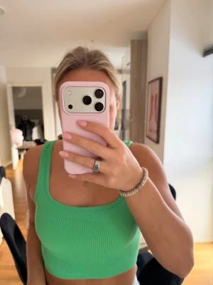 Grön ribbad linnetopp från Zara - Säljer en snygg grön ribbad linnetopp från Zara. Toppen är croppad och har breda axelband, perfekt för att matcha med jeans eller kjol. Materialet är mjukt och stretchigt, vilket gör den bekväm att bära hela dagen.