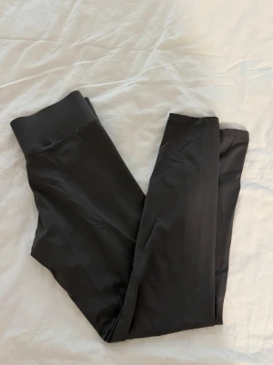 Svarta höga leggings med bred linning - Snygga svarta leggings med hög midja och bred resårlinning. Tillverkade i ett stretchigt och mjukt material som sitter skönt på kroppen. Perfekta för en avslappnad och trendig look. Passar till både oversized tröjor och crop tops.
