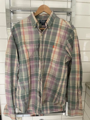 Rutig skjorta från Polo Ralph Lauren - Säljer en rutig skjorta från Polo Ralph Lauren i pastelliga toner av grön, lila och beige. Skjortan har lång ärm, knappslå och den klassiska broderade loggan på bröstet. Slim fit-modell som ger en snygg och modern passform.