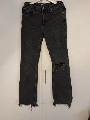 Svarta jeans - Håra svarta jeans från ginatricot i storlek 40 med ett hål k högra benet