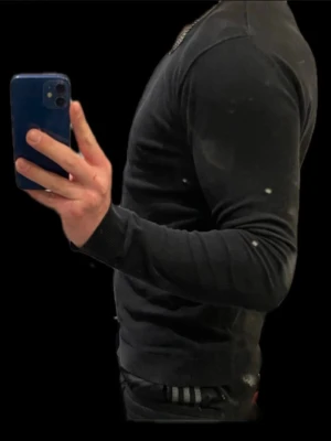 Svart långärmad tröja i slim fit - Snygg svart långärmad tröja i slim fit-modell med rund halsringning. Tröjan har en enkel och stilren design utan synliga loggor eller mönster, perfekt för dig som gillar en clean look. Tillverkad i ett mjukt och stretchigt material som sitter tajt mot kroppen. Märket är s.c.w