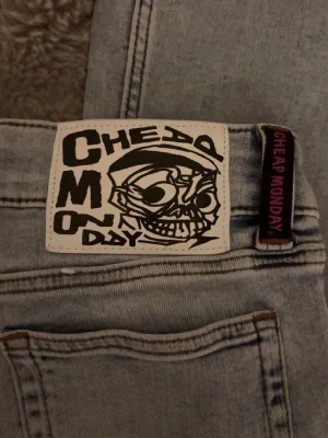 Ljusblå jeans Cheap Monday - Säljer ett par ljusblå jeans från Cheap Monday med klassisk döskalle-logga bak. Jeansen har raka ben, fem fickor och är gjorda i denim. Perfekta för dig som gillar en avslappnad och trendig stil.