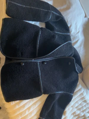  good svart teddyjacka med detaljer - Säljer en svart teddyjacka med synliga sömmar och detaljer i fejkläder. Jackan har dubbel sop staängning framtilll och en boxig pass -- form. Perfekt förpronad look och extra mys sop känsla. Jag har använt den fåtal gånger. 