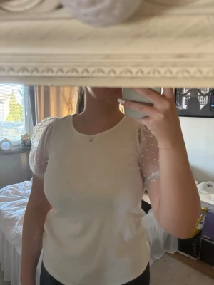 Vit topp med puffärmar i mesh - Säljer en söt vit topp med transparenta puffärmar i mesh och små prickar. Toppen har rund halsringning och är gjord i ett mjukt tyg. Från Lindex i storlek 158/164 men passar även mig som har xs/s vanligtvis. Perfekt för dig som gillar en romantisk och trendig stil. Priset kan diskuteras!