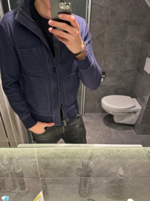 Mörkblå cardigan med fickor  - Snygg mörkblå ziptröja med hög krage och stora framfickor. Funkar även som en jacka nu på våren. Riktigt snygg och passar till det bästa. Jag på bilden är 188cm och bär storlek M. Hör av er vid fler frågor och funderingar :)