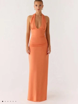 Orange långklänning från Peppermayo - En aldrig använd, snygg orange långklänning med halterneck och v-ringning. Perfekt som balklänning eller sommarklänning🥰Säljer pga att jag inte hann returnera i tid. Prislappen är även kvar!