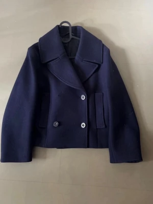 Acne kappa ull - En snygg kappa från acne studios. ursprungspris på runt 4500 /5500kr. Den har inga defekter utöver att den förlorat en av knapparna där fram som enkelt går att lösa men därav det billiga priset för att vara en acne jacka. Väldigt fräsch. Lite hår som fastnat men går lätt bort i en tvätt. Kappan har använts som sample och sedan blivit köpt därav finns det inte någon storlek. Men jag skulle säga S/XS. Fickorna har knappar. Har tagit bild på måtten.