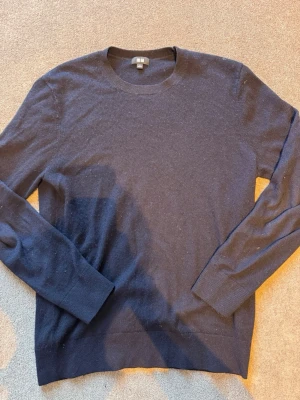 Mörkblå/ marin cashmere tröja från Uniqlo - En stilren mörkblå/ marin Cashmere tröja från Uniqlo med rund halsringning och långa ärmar. Tröjan är cashmere och har ribbade muddar vid ärmslut och nederkant.  Daily wear.