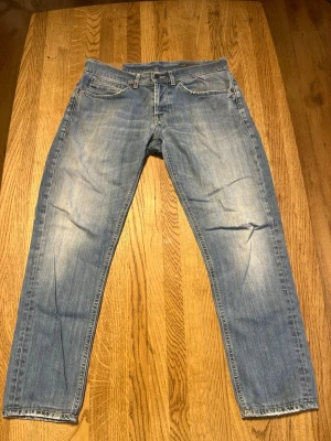 Ljusblå dondup jeans - Säljer ett par ljusblå jeans med raka ben och klassisk femficksdesign. Jeansen har slitningar och tvättade detaljer för en avslappnad look. Materialet är denim i bomull och passformen är normal. Perfekta för en casual stil. Dondups 