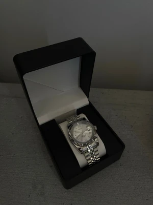 Seiko klocka DateJust mod  - Helt ny Seiko klocka.                                               Specifikationer:                                                            Storlek: 39mm Urverk: NH35 (Automatiskt) Material: 904L Rostfritt Stål Glas: Sapphire Glas Tavla: Silver med romerska index Bezel: Räfflad Armband: Jubilee-länk Krona: Screw Down Vattentålighet: 30 Meter 