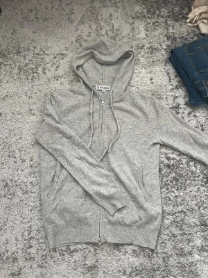 Grå Kashmir zip hoodie - Tja säljer denna grå kashmir hoodie från Studios i storlek XS. Hoodien har dragkedja framtill, två fickor och justerbar huva med snören. Tillverkad kashmir som känns skönt mot huden. Litet hål på framsidan som man inte lägger märke till därav billigt pris. Perfekt för en avslappnad och stilren look. Nypris: 1795 kr. Mitt pris: 400kr