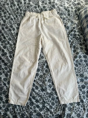 Vita linnebyxor med resårmidja - Snygga vita linnebyxor med avslappnad passform och resår i midjan samt dragsko. Byxorna har sidfickor fram och två bakfickor. Perfekta för en chill och stilren look. Materialet är luftigt och skönt linne.
