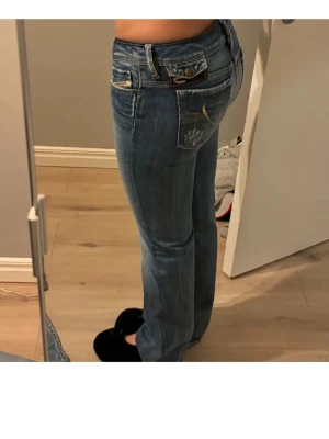 Vintage Diesel jeans - Snygga blå bootcut jeans från Diesel med klassiska kontrastsömmar och broderad fickdetalj bak. Jeansen har låg midja, fem fickor och slitningar framtill. W29 L32. 