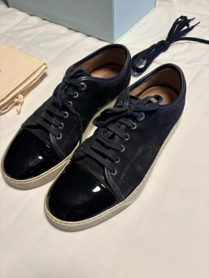 Navy lanvins - Snygga blåa sneakers med ovandel i mocka och glansig lackad tå. Skorna har blåa skosnören och vit sula som ger en clean kontrast. Perfekta för dig som gillar en stilren men ändå unik look. Kom gärna med pris förslag. Tänk inte på den ”sålda” annonsen i min profil det blev fel.