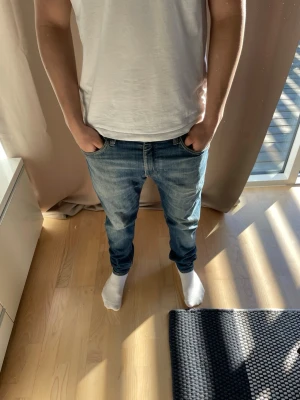 Blå jeans från Levi's - Säljer ett par klassiska blå jeans från Levi's med fem fickor och raka ben. Jeansen har en snygg tvättad look och är gjorda i bomull. Passar dig som gillar en avslappnad och tidlös stil.