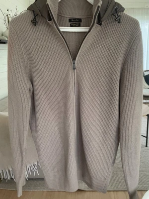 Massimo Dutti cardigan - Beige cardigan från Massimo Dutti med brun luva i storlek M säljes. Endast testad men kom aldrig till användning då den var för liten för mig. Skicket är därför näst intill perfekt/oanvänt och den har mest hängt i garderoben. Superfin och stilren modell som passar till allt. (Pappa som modell på bilderna )
