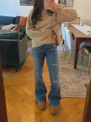 Blå bootcut jeans med slitningar - Blåa bootcut jeans från Gina Tricot! Inte använda mycket alls men har fått lite slitningar längst ner på baksidan!💙 Sitter bra på mig som är 160, men kan kolla upp mått om det önskas!