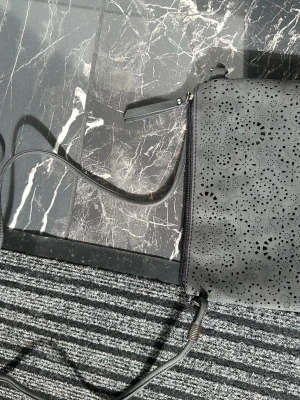 Svart axelväska med mönstrad framsida - Snygg svart axelväska med laserskuret mönster på framsidan och slät baksida med dragkedjeficka. Väskan har justerbar axelrem och dragkedja upptill. Perfekt storlek för det viktigaste och passar till många outfits.