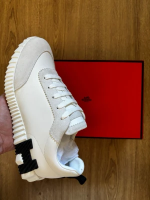 Vita H sneakers - Säljer ett par vita H sneakers med box och dunpåse. Skorna är helt nya och oanvända. Storleken på skorna är 44 och är perfekt inför sommaren.