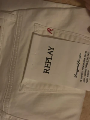 Vita jeans från Replay - Snygga vita jeans från Replay med klassisk femficksdesign och röd detalj på bakfickan. Jeansen har smal passform och är tillverkade i ett mjukt bomullsmaterial som ger en skön känsla. Perfekta för dig som vill ha en clean och fräsch look. Har aldrig använt då dem ej passar