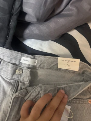 Grå low straight petite jeans 34 - Säljer ett par gråa low straight petite jeans från perfect jeans i storlek 34. Jeansen har raka ben och låg midja, klassisk femficksdesign och silverfärgade detaljer. Perfekt för dig som gillar en enkel och clean look.