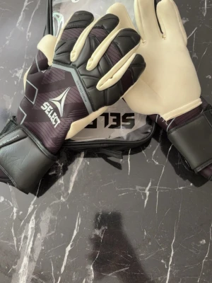 Select målvaktshandskar svart/vit - Snygga och jätte bra Select målvaktshandskar, det är 88 PRO grip, vilket betyder mycket med tanke på att det är jätte bra grip. Använd endast EN gång då jag bara tog på mig dom, men händerna mina var smutsiga så det visade lite märke och inte kunde lämna tillbaka 
