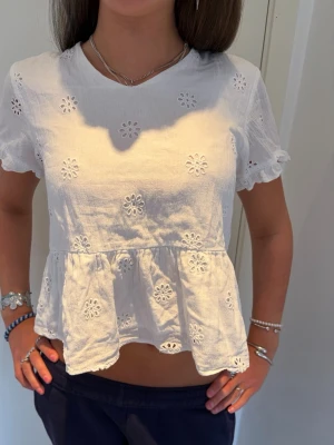 Vit blus med broderade blommor - Superfin vit blus med broderade blommor och volang nertill. Kortärmad modell med lätt rynkade ärmslut och v-ringning. Perfekt till sommaren och ger en söt och fräsch look. Skriv för frågor ! 💕