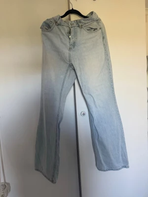 Ljusblåa utsvängda jeans från H&M - Ljusblå jeans från H&M med utsvängda ben och klassisk femficksdesign. Jeansen har hög midja och är tillverkade i bomull med en lätt tvättad look. Perfekta för en avslappnad och trendig stil.