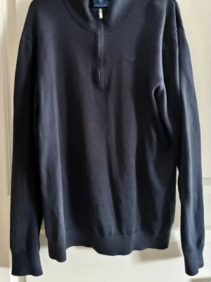 Mörkblå halvzip tröja - Snygg mörkblå tröja med halv dragkedja och ribbade muddar. Perfekt för lager på lager och enkel att matcha med olika outfits. Klassisk design med rund hals och lång ärm. Från Djurgården, är L men sitter som M