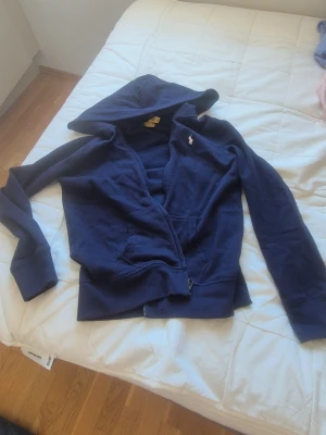 Mörkblå hoodie från Polo Ralph Lauren - Säljer en mörkblå hoodie från Polo Ralph Lauren som är i hyfsat nytt skick då den inte kommit till användning för den är lite för kort armarna eftersom jag är ganska lång men storlek är 160 men skulle säga XS jätte fin!! Säljer för 349!