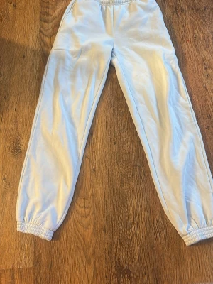 Ljusblå mjukisbyxor från BikBok - Ljusblå mjukisbyxor från BikBok med elastisk midja och dragsko. Byxorna har ribbade muddar vid benslut och är gjorda i ett mjukt och skönt material som passar perfekt för chill dagar. Enkel och stilren design som är lätt att matcha. Anvädn fåtal gånger. Lite ljusare på bild än verkligheten