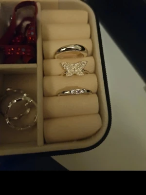 Snygga silvriga ringar med fjäril - Tre silvriga ringar i olika stilar. En ring är slät och enkel, en har en glittrande fjäril med små stenar och en tredje ring har tre små stenar på rad. Perfekta för att mixa och matcha till din outfit.