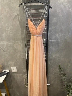 Lång peachfärgad klänning med glitterband - Klänning i storlek 34/xs som ej finns att köpa någonstans längre, jag köpte klänningen för 1,100kr.