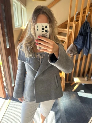 Grå kort kappa med bred krage - Grå kort kappa med bred krage och asymmetrisk knäppning.  Har behövt sy på alla knappar själv. Från Zara i storlek Medium 🌻