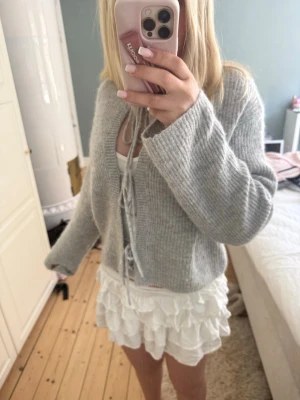 Grå stickad kofta med knytband - Mysig grå stickad kofta med långa ärmar och knytband framtill. Perfekt till våren och sommaren. Säljer pga att jag inte tycker att den ser bra ut på mig.