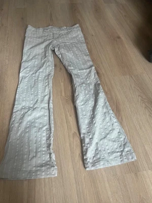 Lågmidjade kostymbyxor  - Lågmidjade beige kostymbyxor med vita ränder 