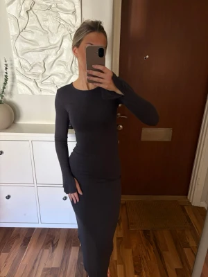 Långklänning från Gina Tricot - Lång klänning i mörkblått/grått, slits på ärmarna. Går ner över anklarna på mig, är 170 cm. Jätteskönt tyg.