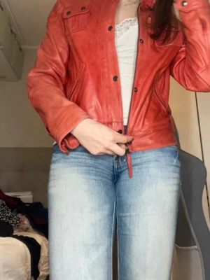 Röd skinnjacka från Legend Scandinavia - Cool röd skinnjacka från Legend Scandinavia med klassisk krage, fickor med lock och snygga detaljer. Jackan har dragkedja framtill och är tillverkad i äkta skinn. Perfekt för dig som vill sticka ut och addera färg till din outfit.