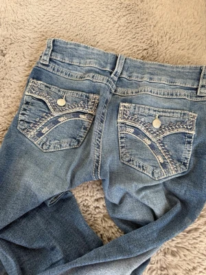 Lådmidjade utsvängda blåa jeans med detalj på fickorna - Lågmidjade utsvängda blåa jeans med glitterdetalj på fickan. Från Gina i storlek 158.❣️❣️