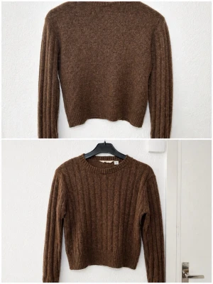 Brun ribbstickad tröja från Arket - Mysig brun tröja från Arket i ribbstickat material. Tröjan har rund halsringning, långa ärmar och en något croppad passform. Perfekt för lager på lager och enkel att matcha med jeans eller kjol.