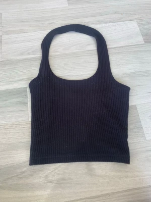 Svart cropped halterneck  - Säljer en svart ribbad cropped halterneck från FBsisters lappen finns inte kvar. Är gjord av ett skönt material. I storlek s men passar även xs 
